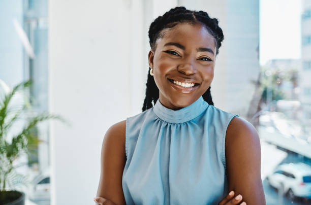 confident young black businesswoman standing at a window in an office alone